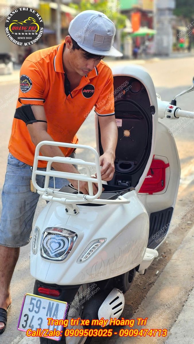 Chiếc baga sau trắng đang được nhân viên lắp đặt lên Vespa Justin Bieber