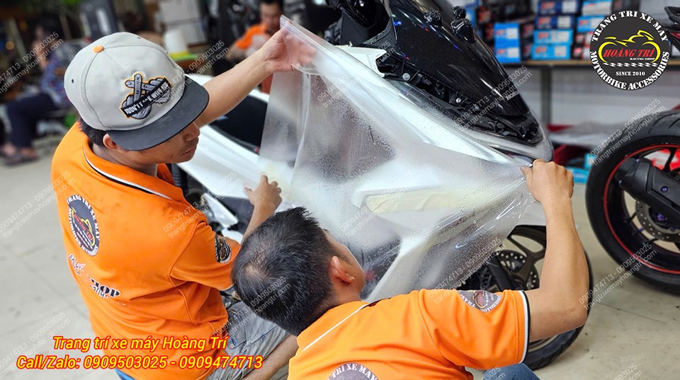 Nhân viên đang căn chỉnh lớp keo PPF sao cho vừa khít với phần dàn áo.