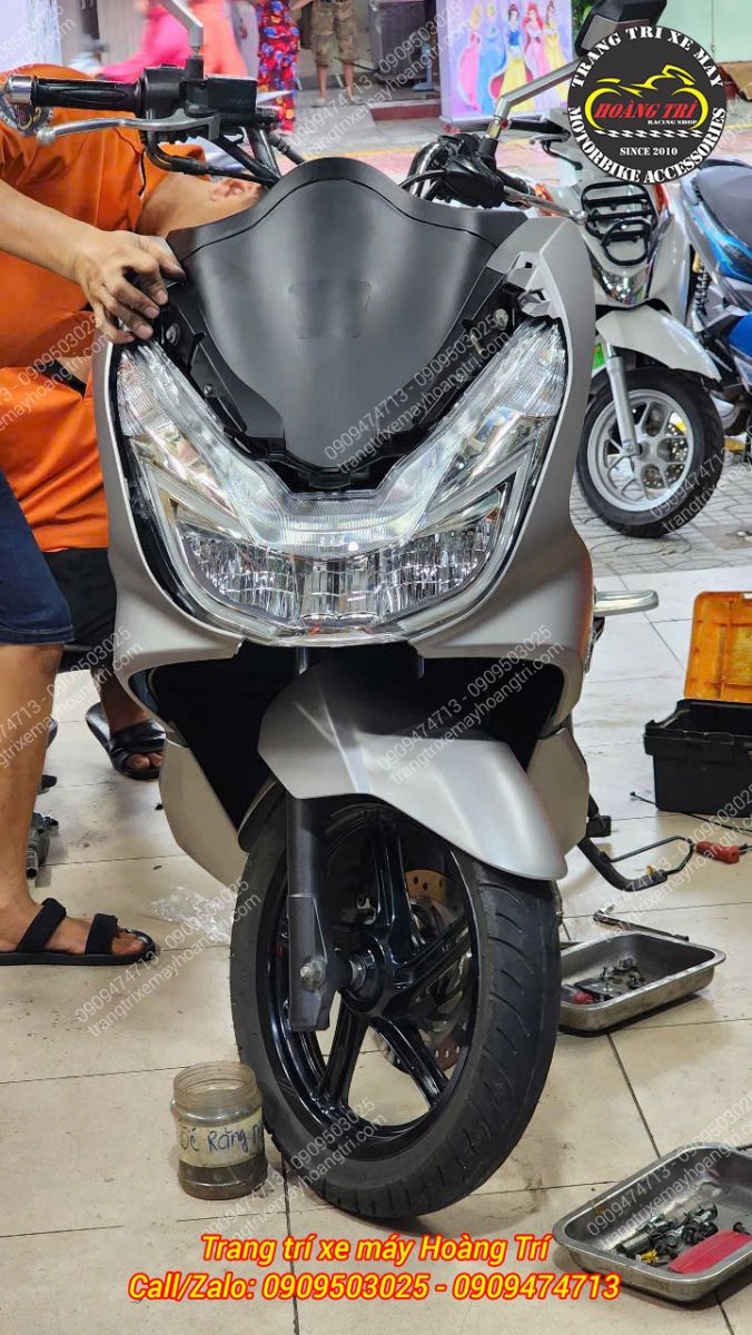 Sau khi thay đèn pha PCX 2014, nhân viên đang hoàn thiện phần dàn áo cho xe