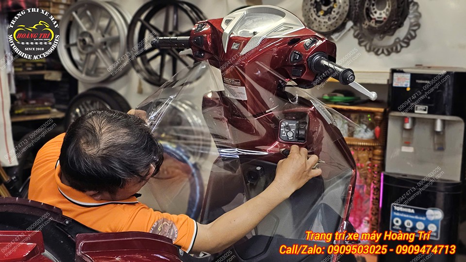 Nhân viên đang thực hiện dán keo tại vị trí ổ khóa của xe Lead