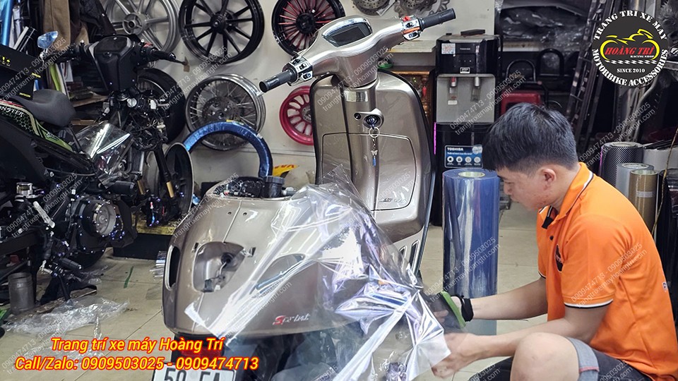 Nhân viên đang thực hiện dán keo ở phần 2 bên hông xe Vespa TFT