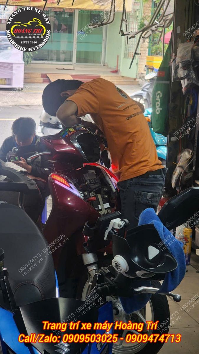 Nhân viên Hoàng Trí Shop đang thi công độ đèn bi cầu cho SH Mode, đảm bảo căn chỉnh chuẩn xác