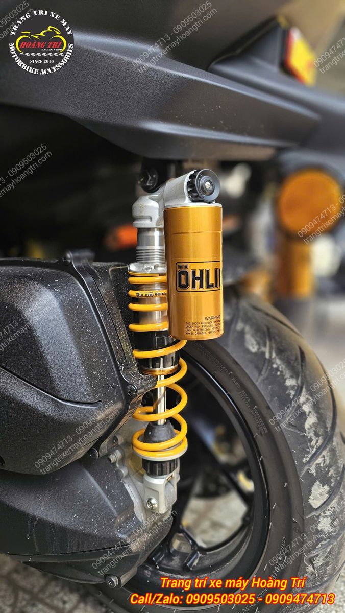 Cận cảnh phuộc Ohlins XMAX với bình dầu vàng đặc trưng, tạo điểm nhấn nổi bật phía sau