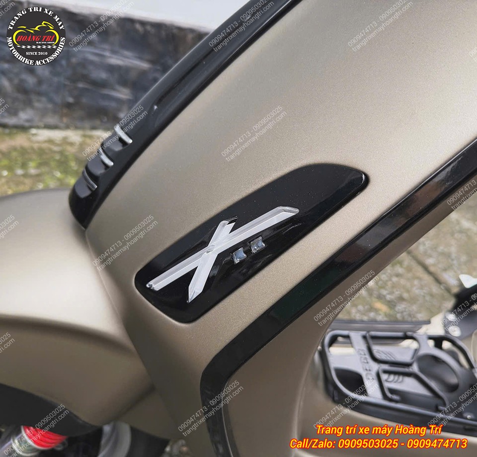 Cận cảnh logo chữ X trên nền đen trong cụm xi nhan trước chữ X, tạo điểm nhấn