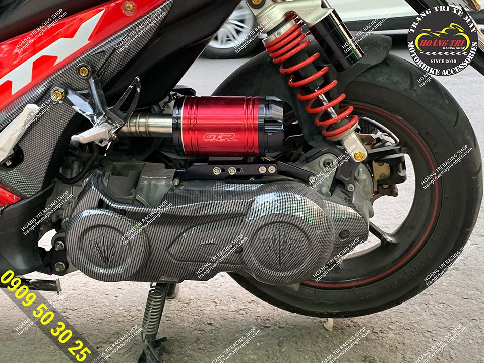 The red cylindrical muffler is mounted on the red NVX with a splash of color